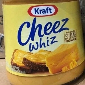 A container of cheez whiz cheese on the counter.