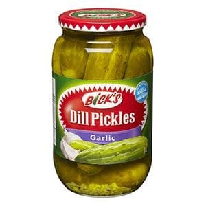 A jar of pickles with garlic on top.
