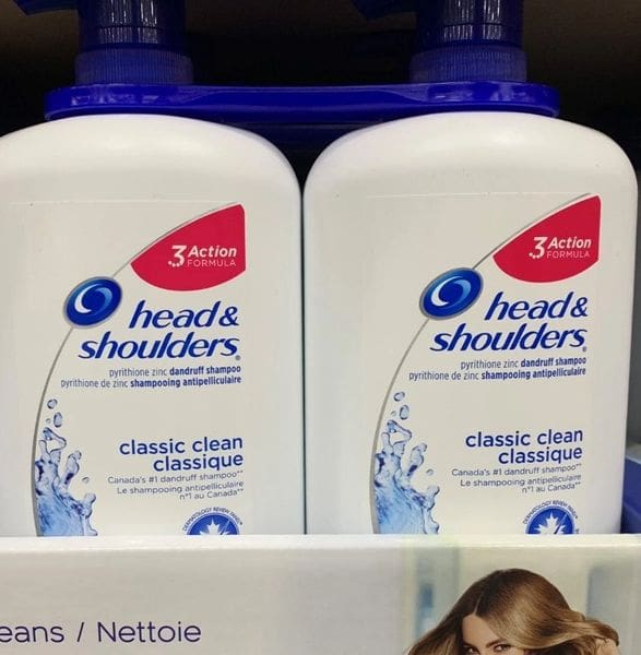 A shelf with two bottles of head and shoulders shampoo.