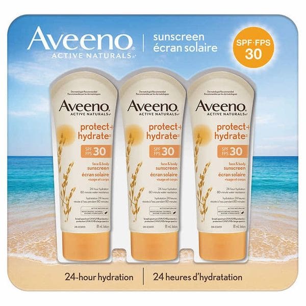 A trio of aveeno sunscreen products on top of a beach.