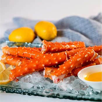 A plate of crab legs on ice with lemons.