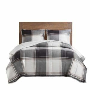 A Canadiana Otto Reversible Comforter Set plaid comforter set on a wooden bed.